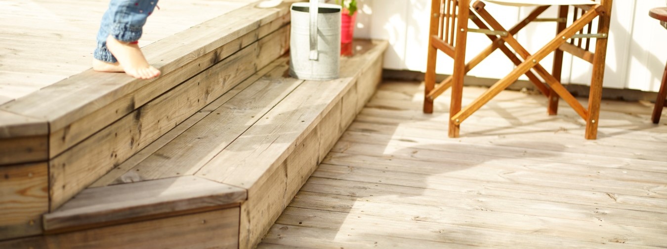 Barneføtter som løper ned en terrassetrapp laget av termofuru fra Moelven