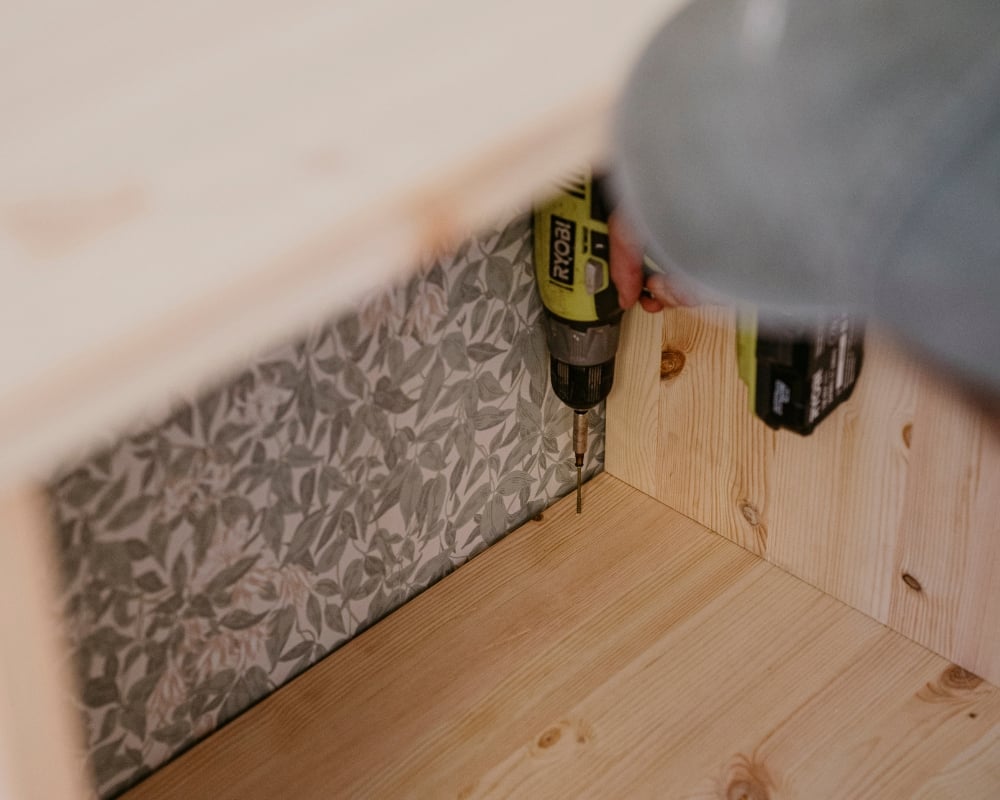 En trähylla skruvas fast i en ram