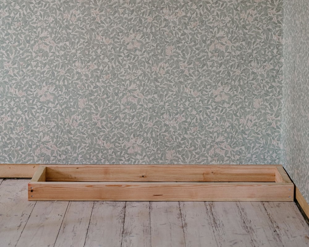 En träram placerad i ett hörn av ett rum