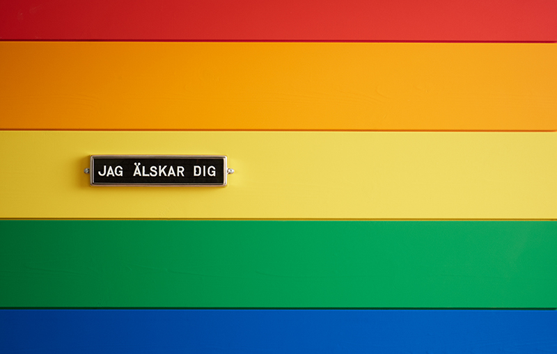 En vägg med träpanel i regnbågens färger