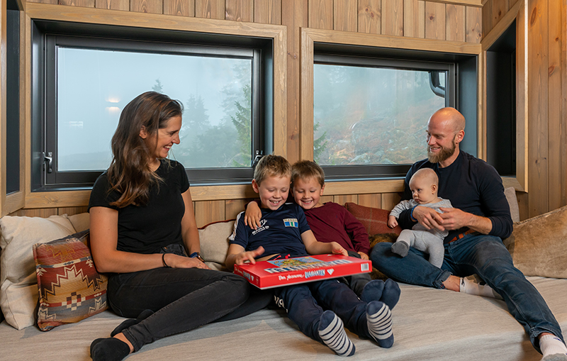 Martin Johnsrud Sundby, kona Marieke og de tre sønnene spiller brettspill ved vinduet på hytta.