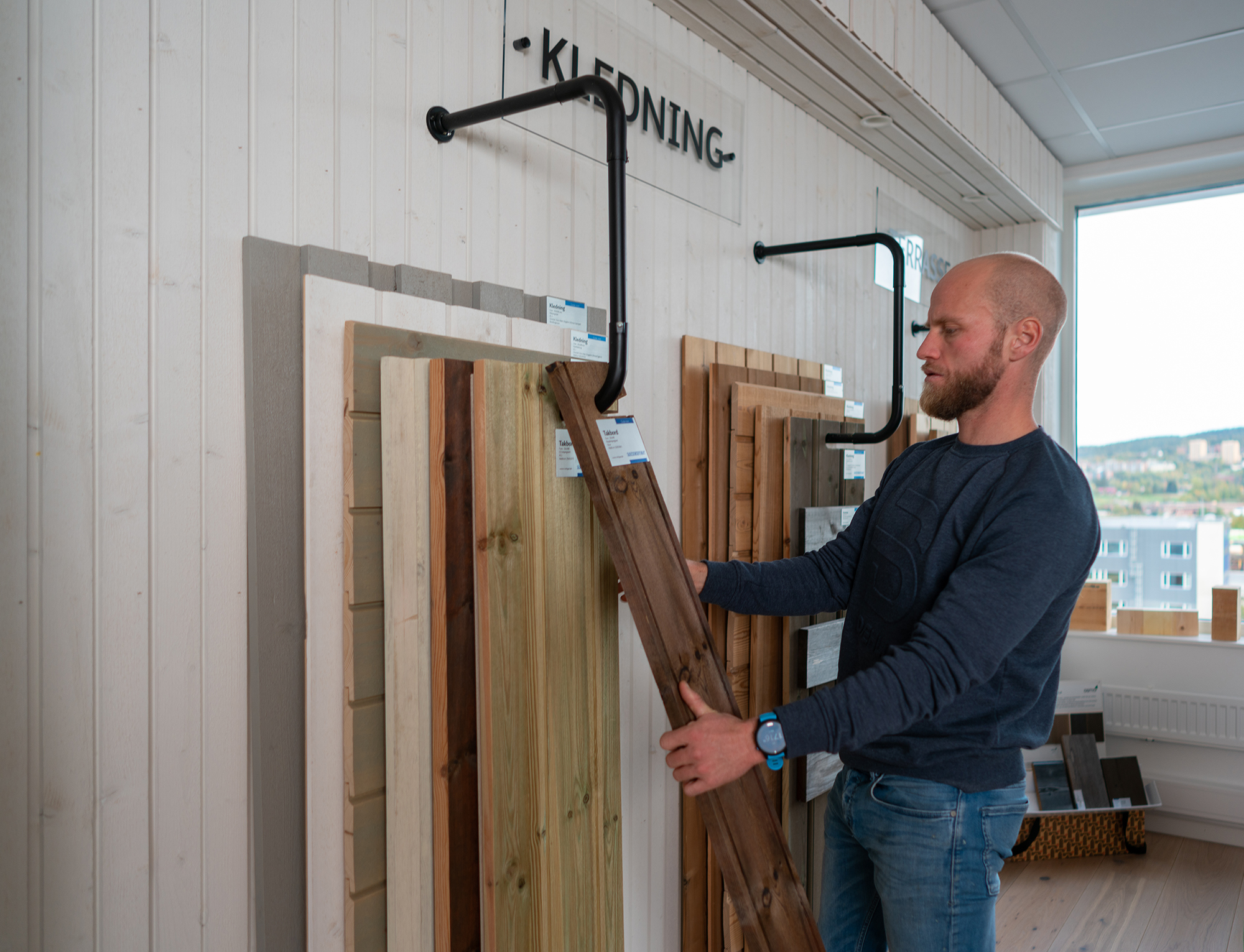 Martin Johnsrud Sundby med en materialprøve på kledning i hånda.