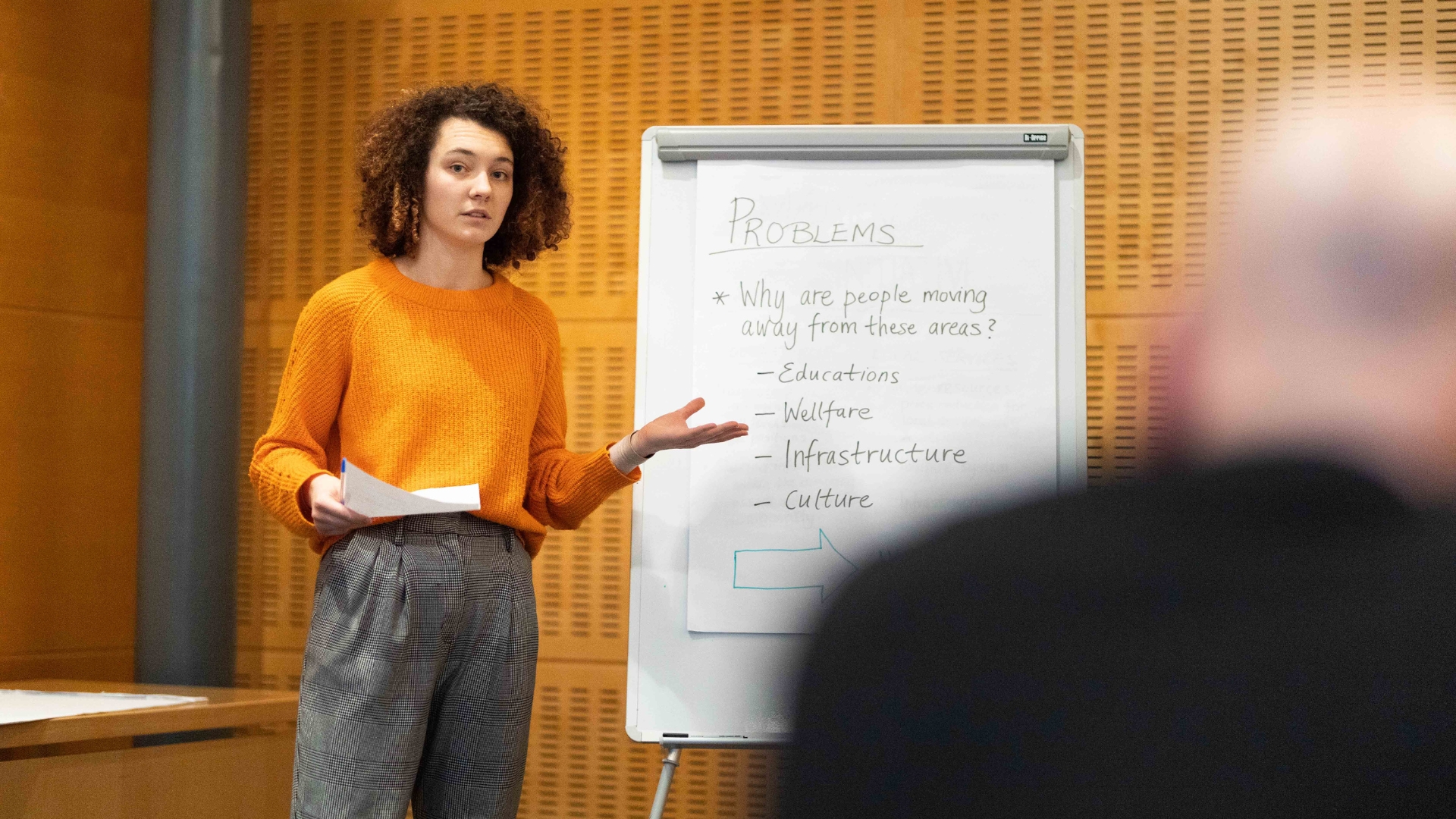 Student i orange tröja som pitchar för en publik