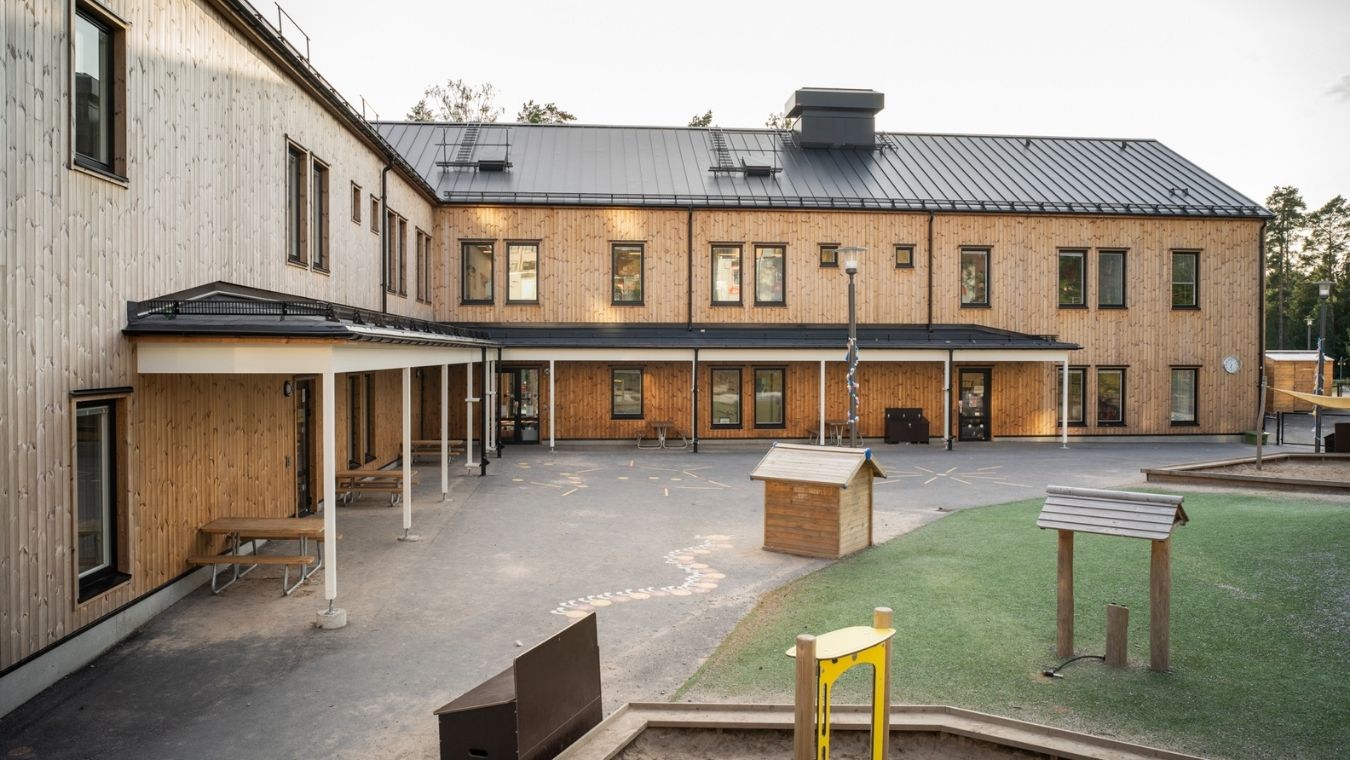 Utsidan av en skolgård, ny förskola i ljus träfasad