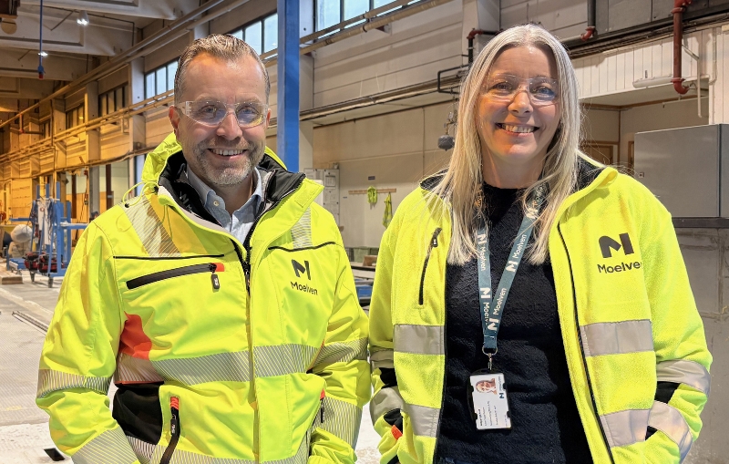 Mann og kvinne i synlighetstøy i fabrikk hos Moelven.