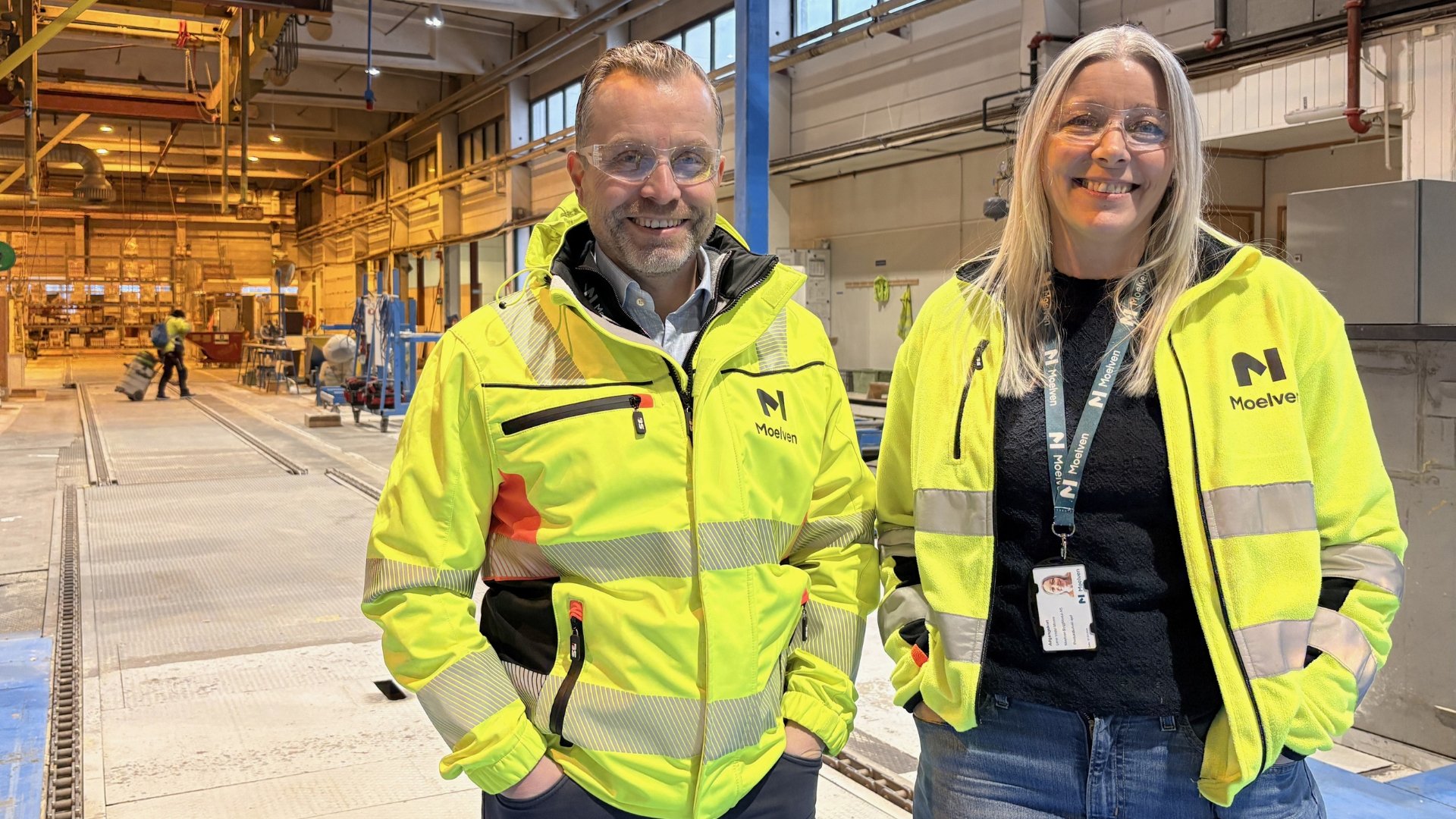 Mann og kvinne i synlighetstøy i fabrikk.