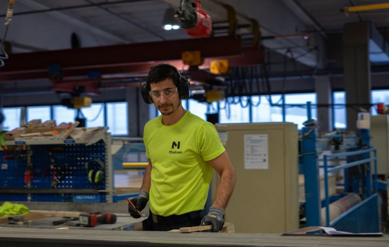 En produksjonsarbeider med hørselvern inne i et fabrikklokale