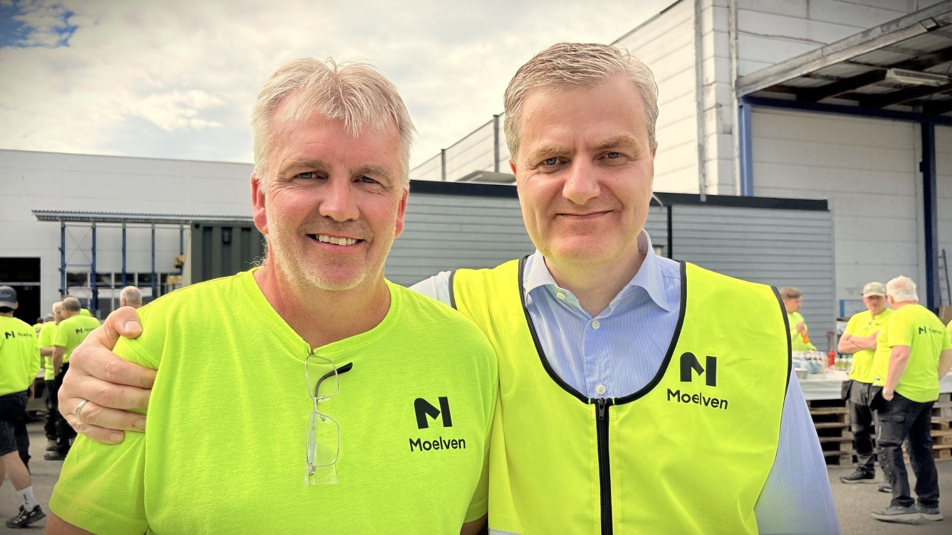 To menn ikledd synlighetstøy utenfor fabrikken hos Moelven Byggmodul.