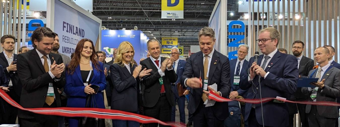 En smilende forsamling mennesker hvor det klippes snor for å åpne norsk paviljong på en kongress.