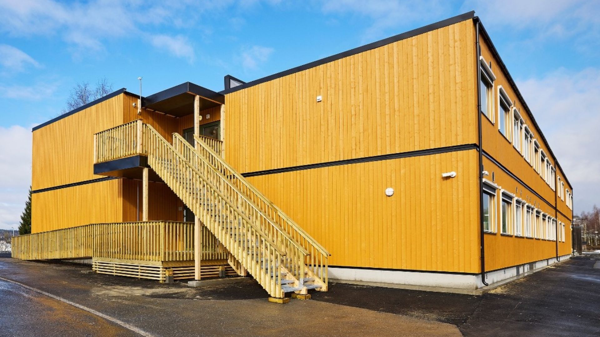 Fasaden på en modulbygd skole. Bygget har to etasjer og har okergul trekledning.