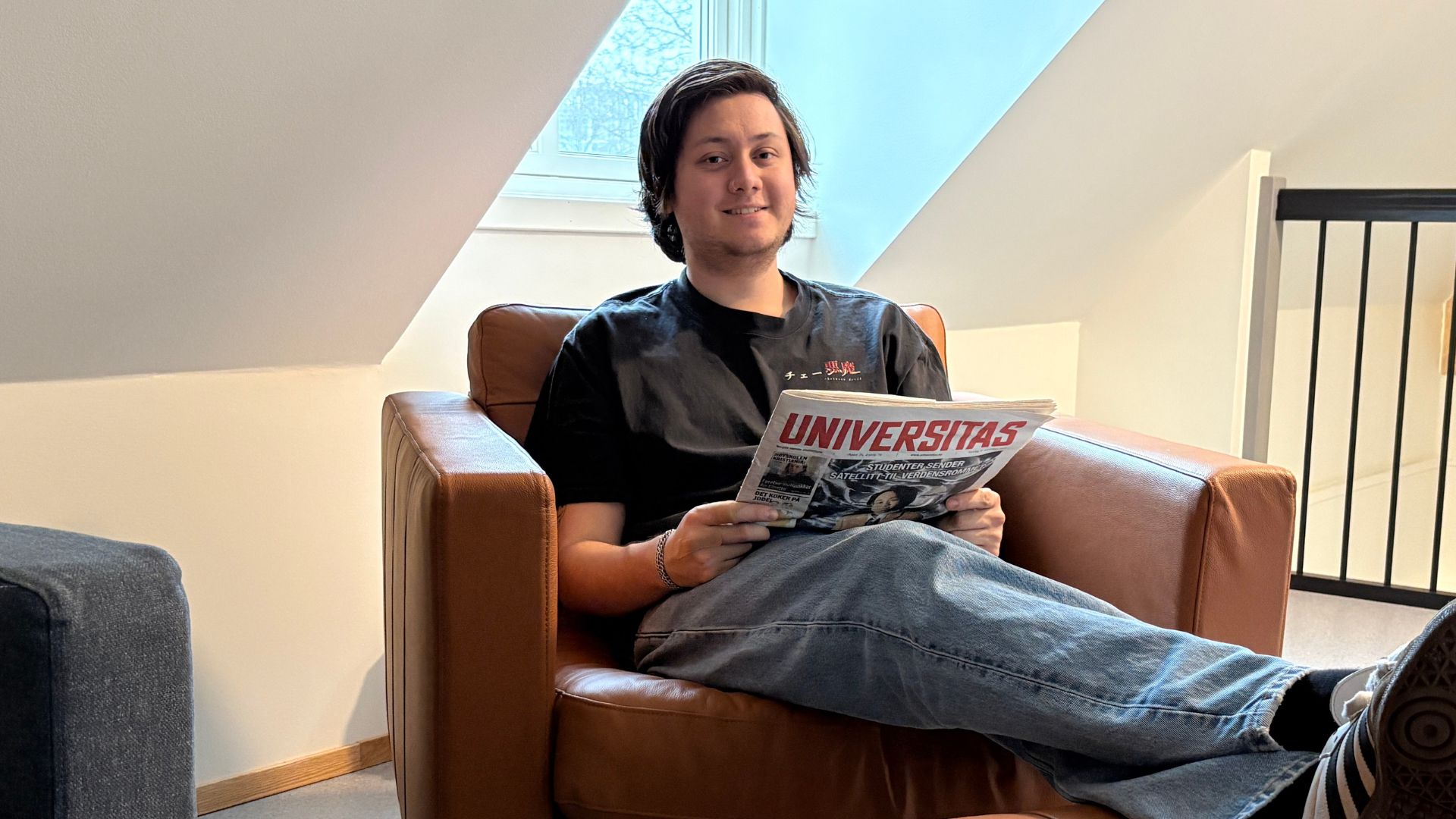 Person som sitter i en stol og holder avis i hendene. 