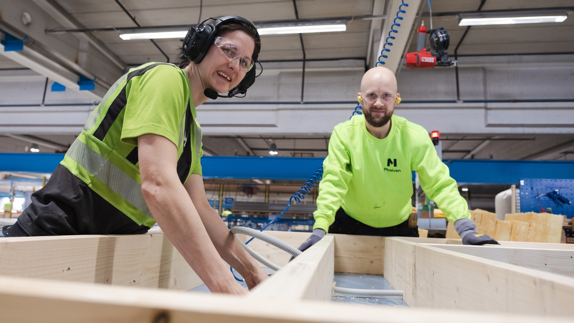 Eine Frau und ein Mann bauen in einer Fabrik den Rahmen für ein Bauelement.