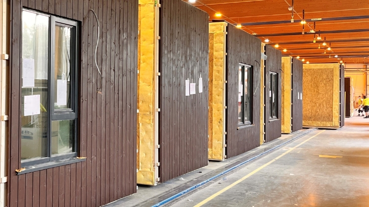 Holzmodule, die hintereinander auf einem Fabrikband stehen.