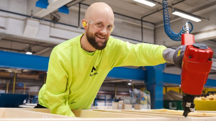 Ein lächelnder Fabrikarbeiter stellt ein Holzmodul her