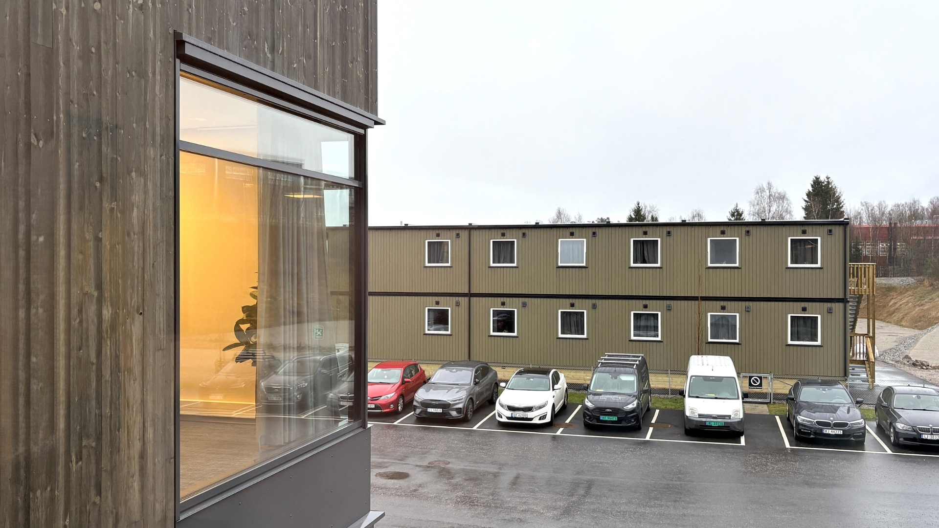 Udvendigt view af boligpavilloner til indkvartering med parkeringsplads og adgang til boligenheder.