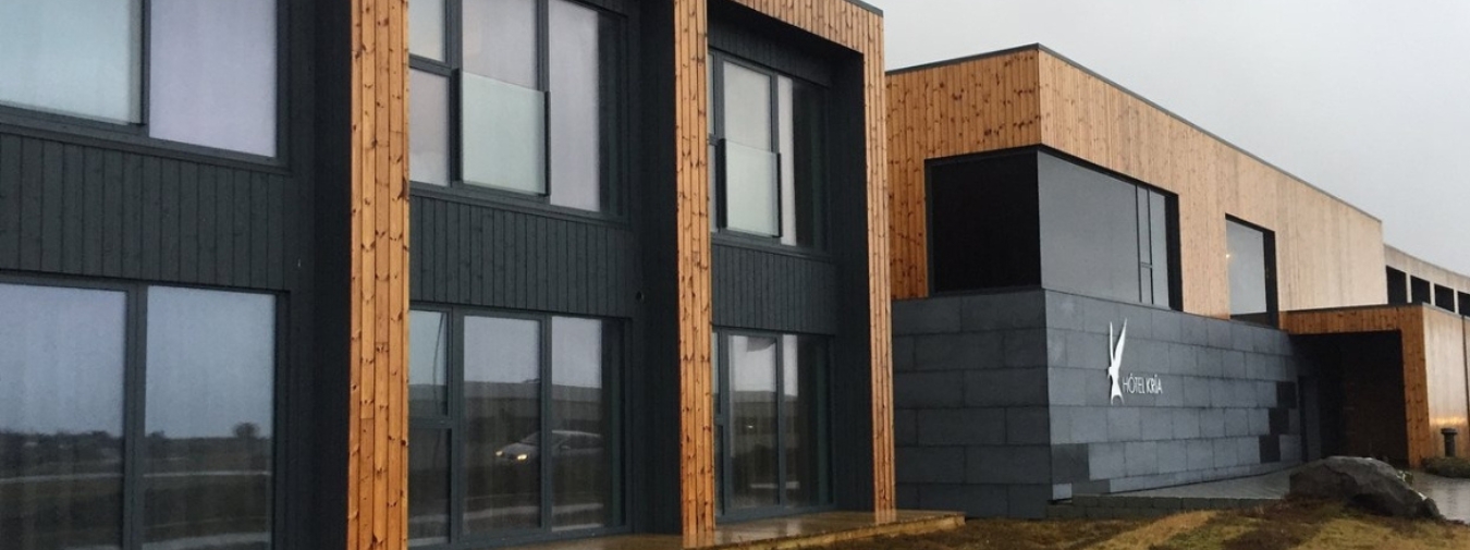 Two-story modular building with large windows, light brown and black wood cladding.