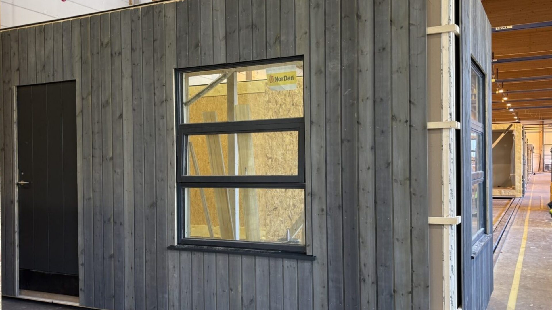 Forframleidd byggingareining með viðarklæðningu inni í verksmiðju.