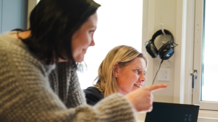 Двоє усміхнених колег, які дивляться в одному напрямку.