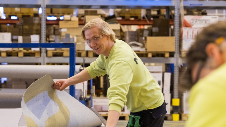 Fabrikkarbeider som holder i gulvbelegg.