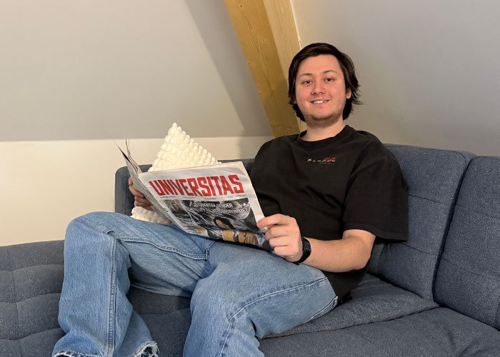 Person som sitter i hjørnet av en sofa og leser avisen.