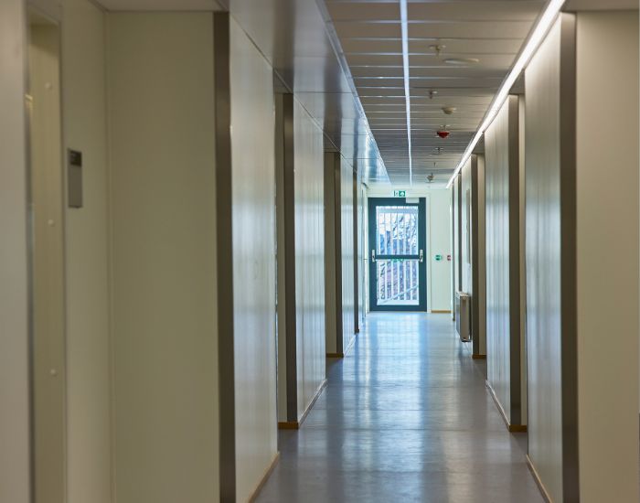Korridor med dør i enden som slipper lys inn.