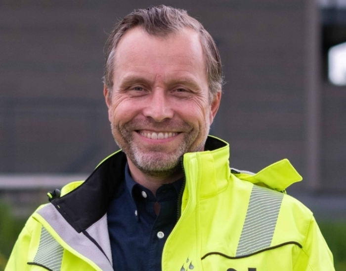 Smilende mann i Moelven synlighetsjakke.