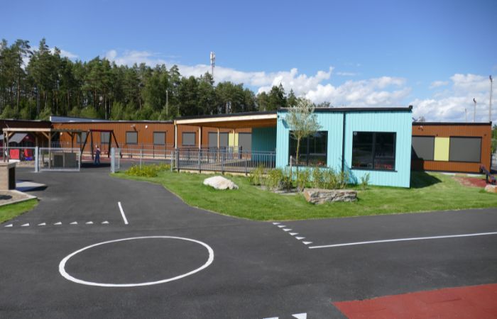 Fasade og uteområde til Ringvoll barnehage, bygget med prefabrikkerte moduler fra Moelven Byggmodul. Kostnadseffektiv bygging med kort byggetid og høy kvalitet.