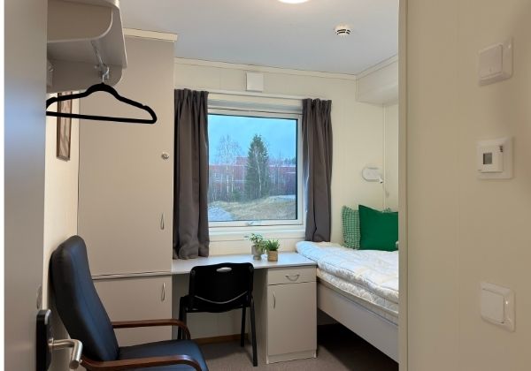 Komfortabel hybel i boligrigg med skrivebord, seng og oppbevaringsplass – ideelt for arbeidere.