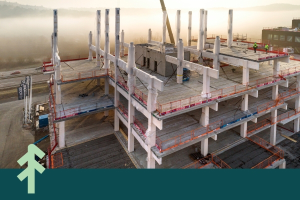 limträstomme som håller upp betongbjälklag i vackert solljus.