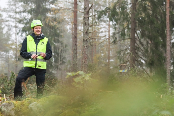 Person i varselkläder i grön skog