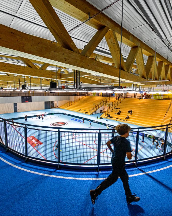 Inuti Österåker multiarena, barn som springer på blått golv, synliga limträbalkar i taket
