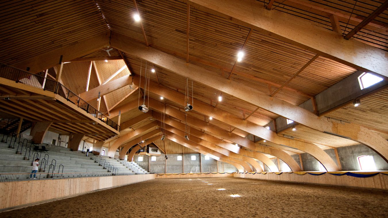 Ridhus i mörkt trä med lampor i taket, person på lektaren