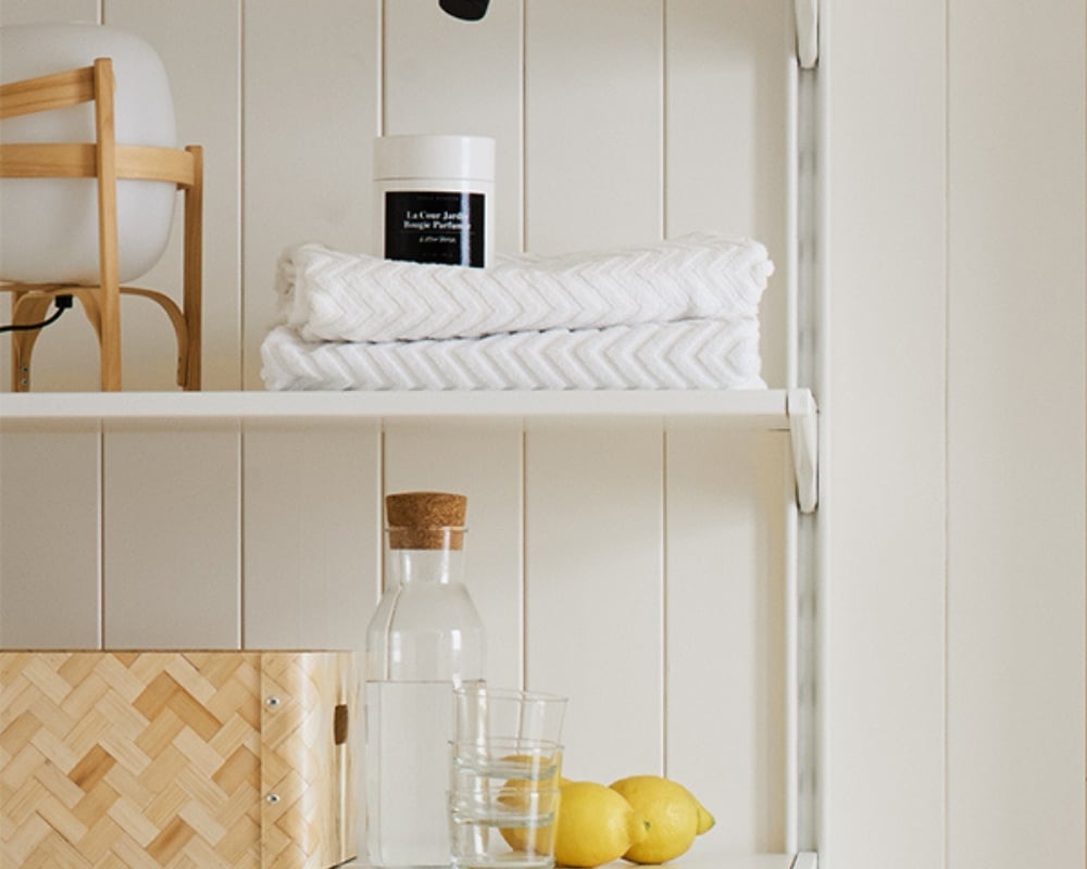 en vägg med vit träpanel och en hylla med gymdetaljer som hopprep, handduk, karaff med vatten