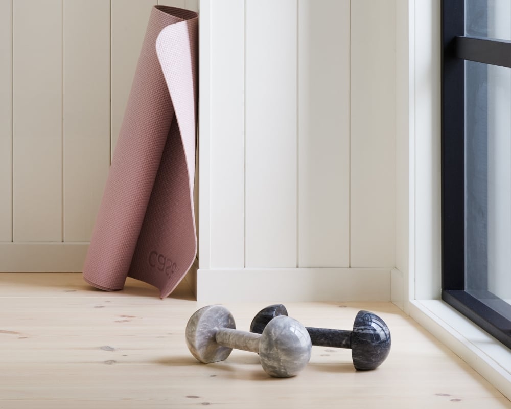 hemmagym med vit träpanel och ljust trägolv, hantlar och yogamatta