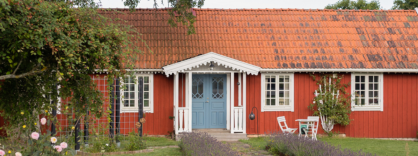 Ett rött torp med tegeltak och blå dörr