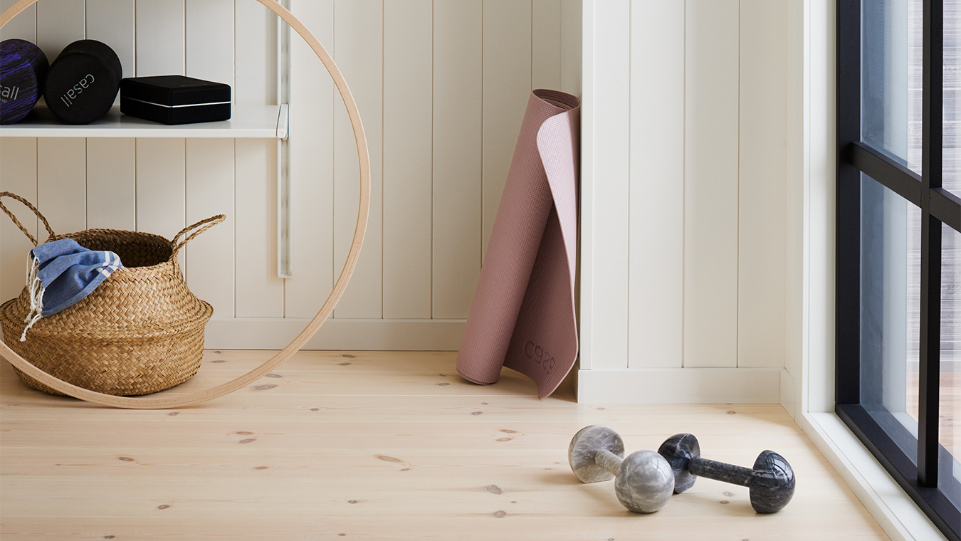 Ett hemma gym med trägolv och vit träpanel