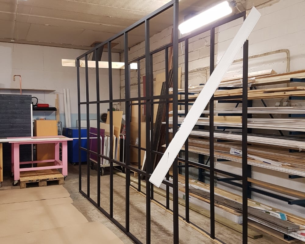 Skiljevägg av trä, målad i svart, monterad