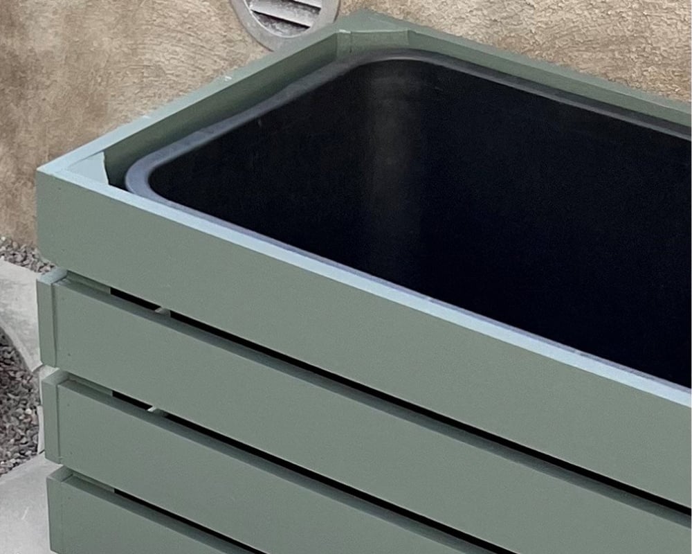 En blomlåda i grönt, med en svart balja