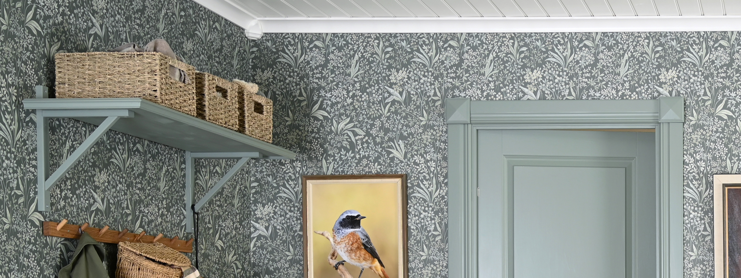 En grön hatthylla på en mönstrad tapet och grön dörr