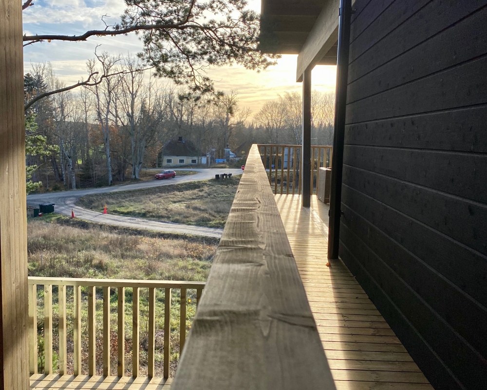 En vägg av ett hus med svart limträpanel och en trall