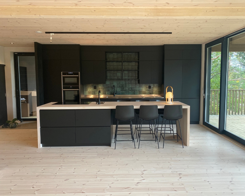 Ett kök med trägolv och träpanel i taket, kök med svart interiör