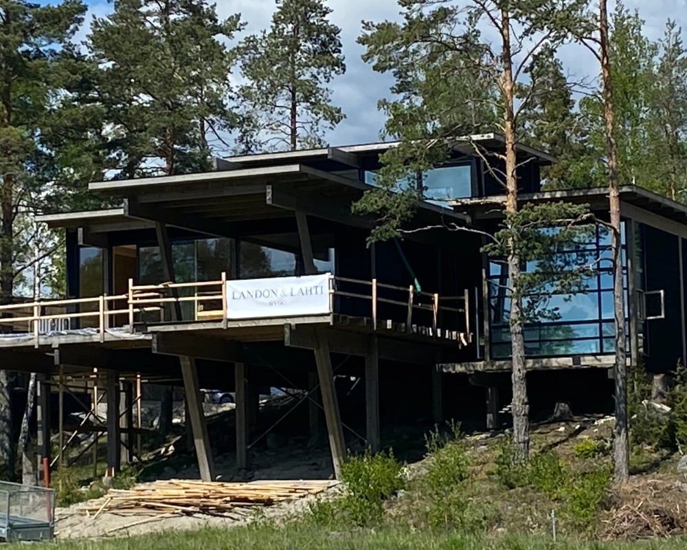 Ett hus med svart limträpanel i skogen