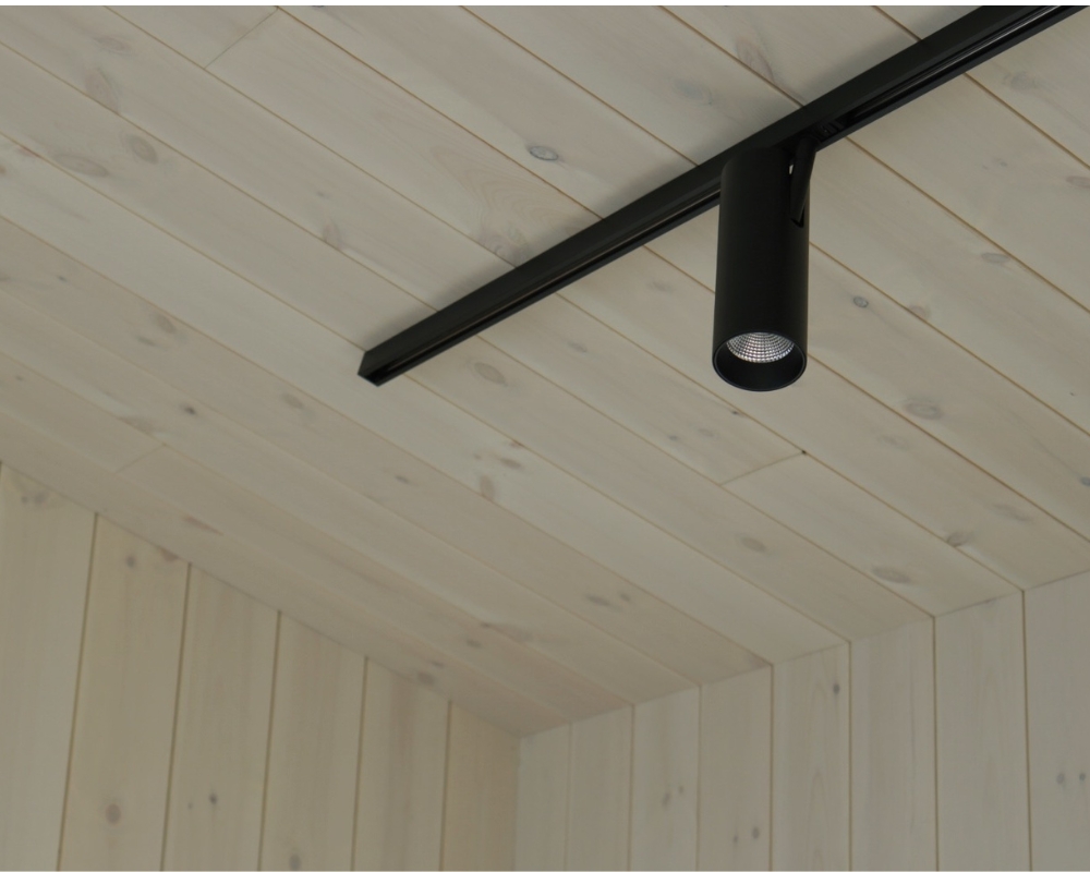 Ett tak och väggar i trä, en svart spotlight