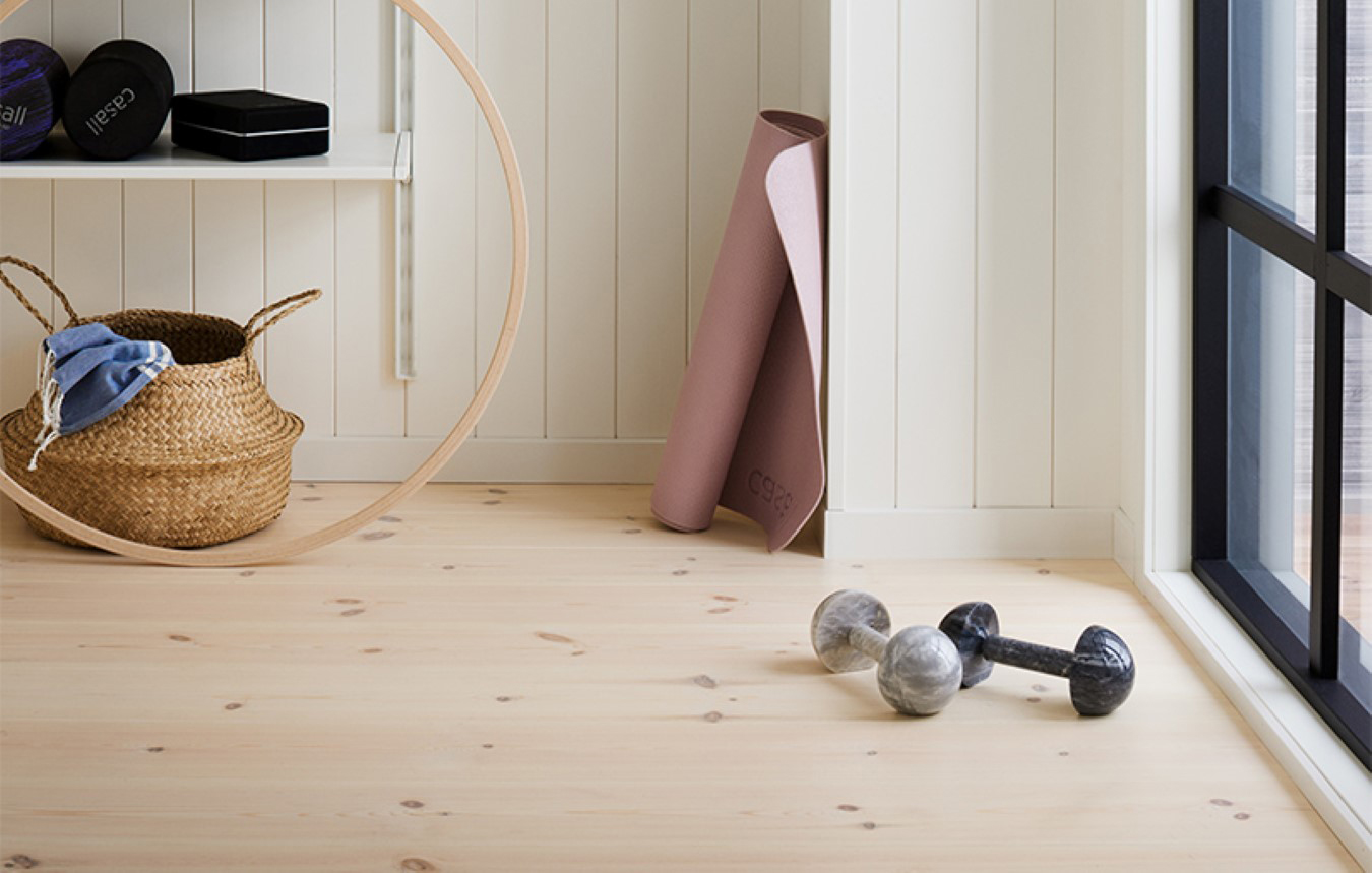 Hemmagym med ljust trägolv och vita träpaneler