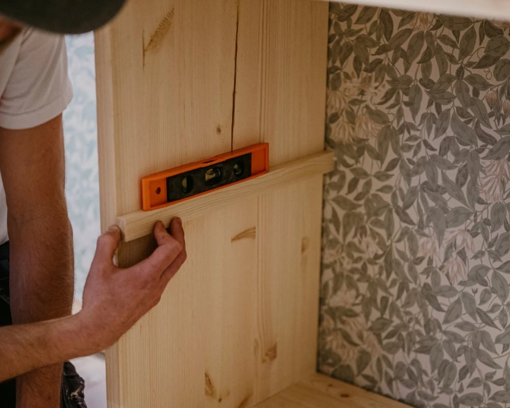 En stödlist monteras i en hylla för att kunna placera ett hyllplan på