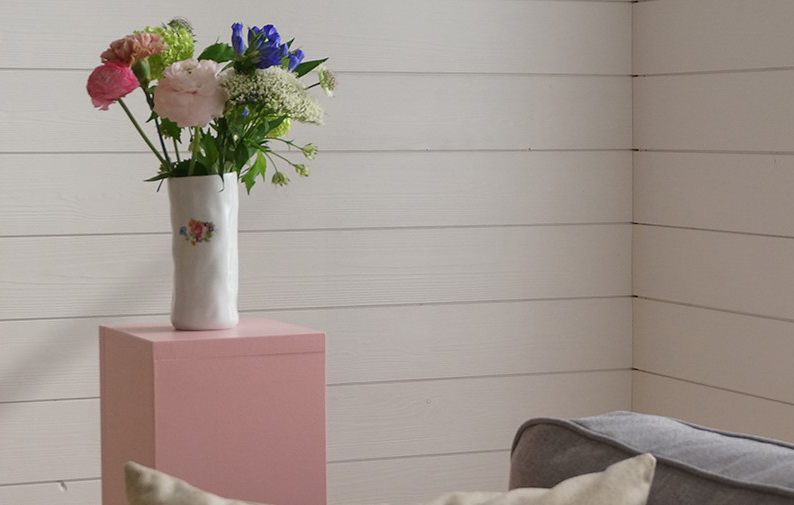 En rosa piedistal och en vas med blommor