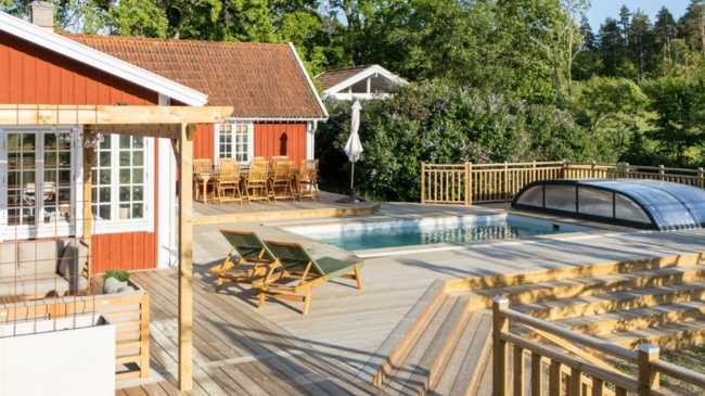 Rött hus med trall och poolområde