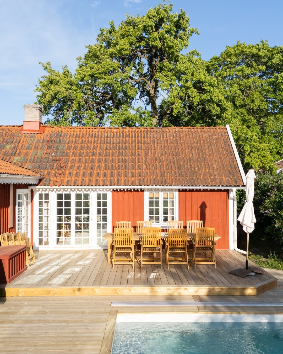 Rött hus med tralll, utemöbler och pool