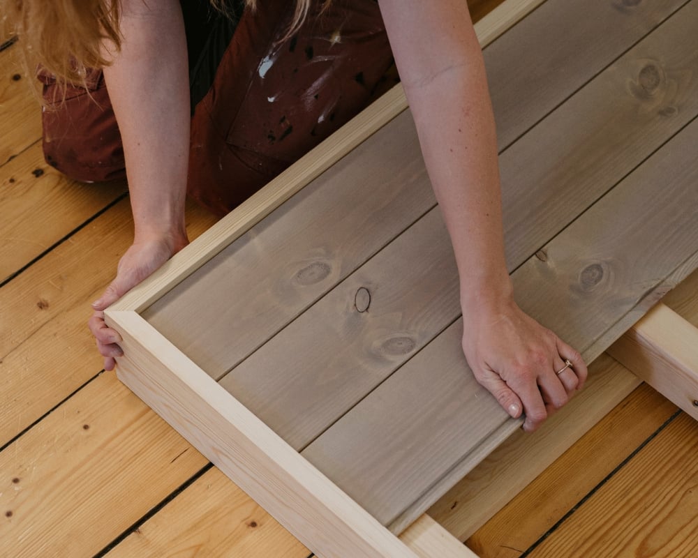 en kvinna monterar ihop en sänggavel av trä