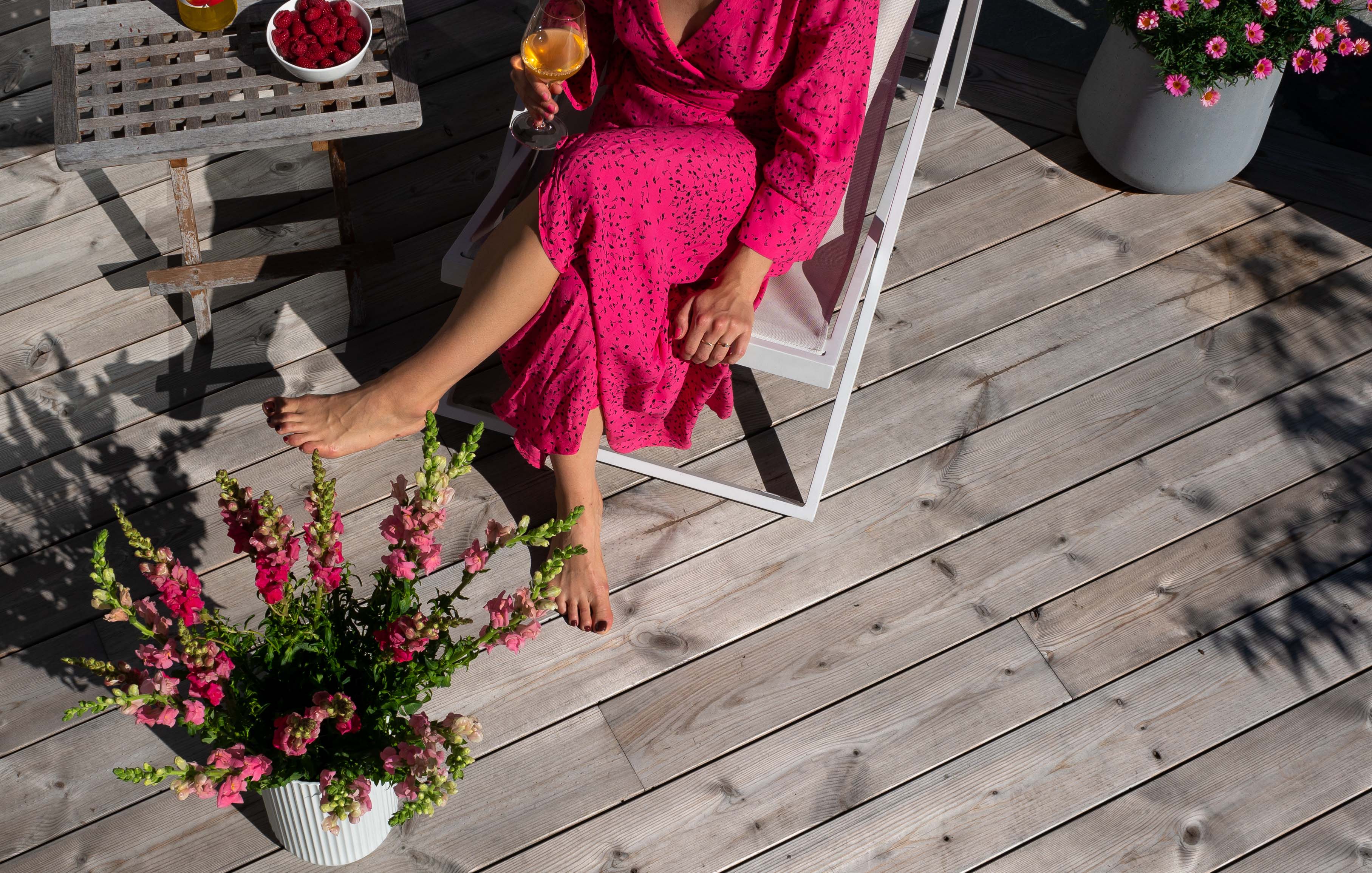 Kvinna sitter i solstol på altan av ThermoWood
